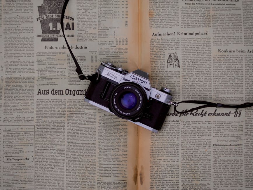 Classic Canon AE-1 film camera resting on vintage newspaper surface.