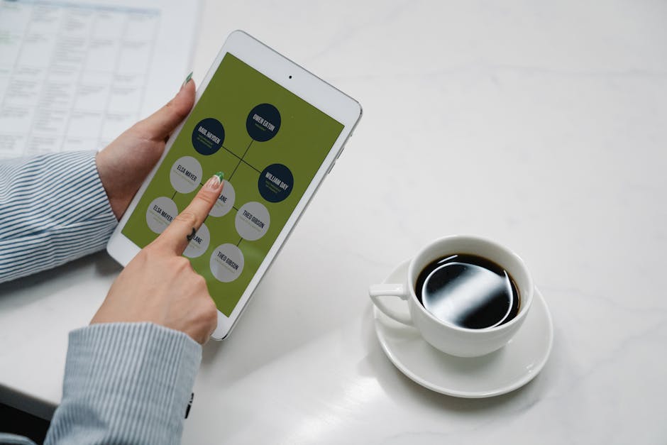 Hands holding a tablet with a diagram, next to a cup of black coffee on a desk, symbolizing modern work life.