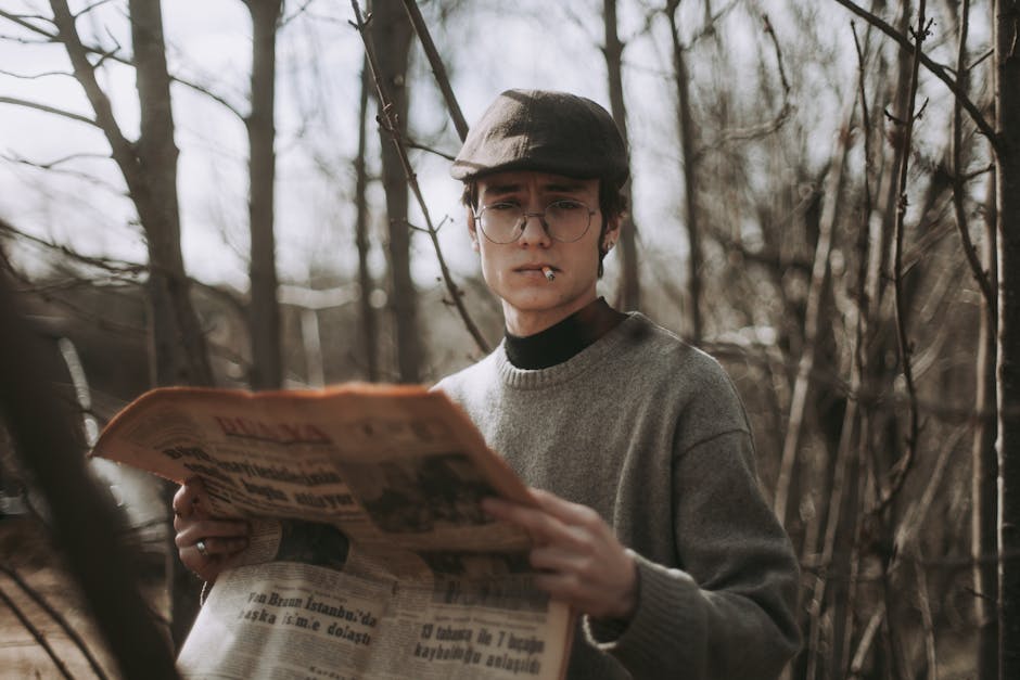 Portrait of a man in vintage attire holding a newspaper in a forest setting.